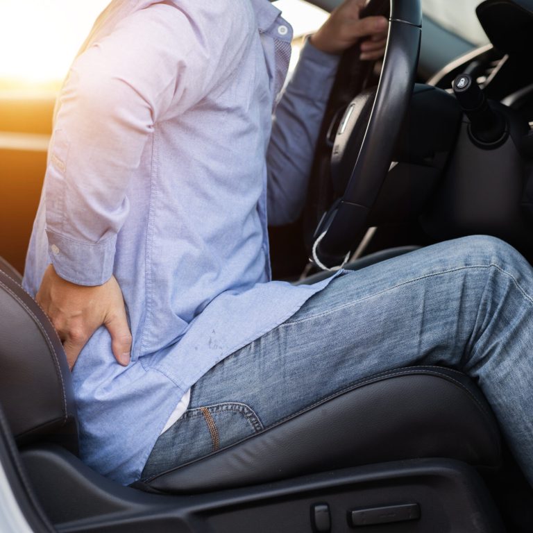 Close-up shot of a man with severe back pain after a long drive.